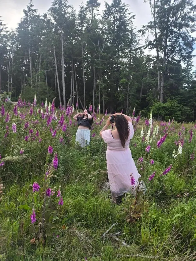 A woman photographing her friend among tall foxgloves