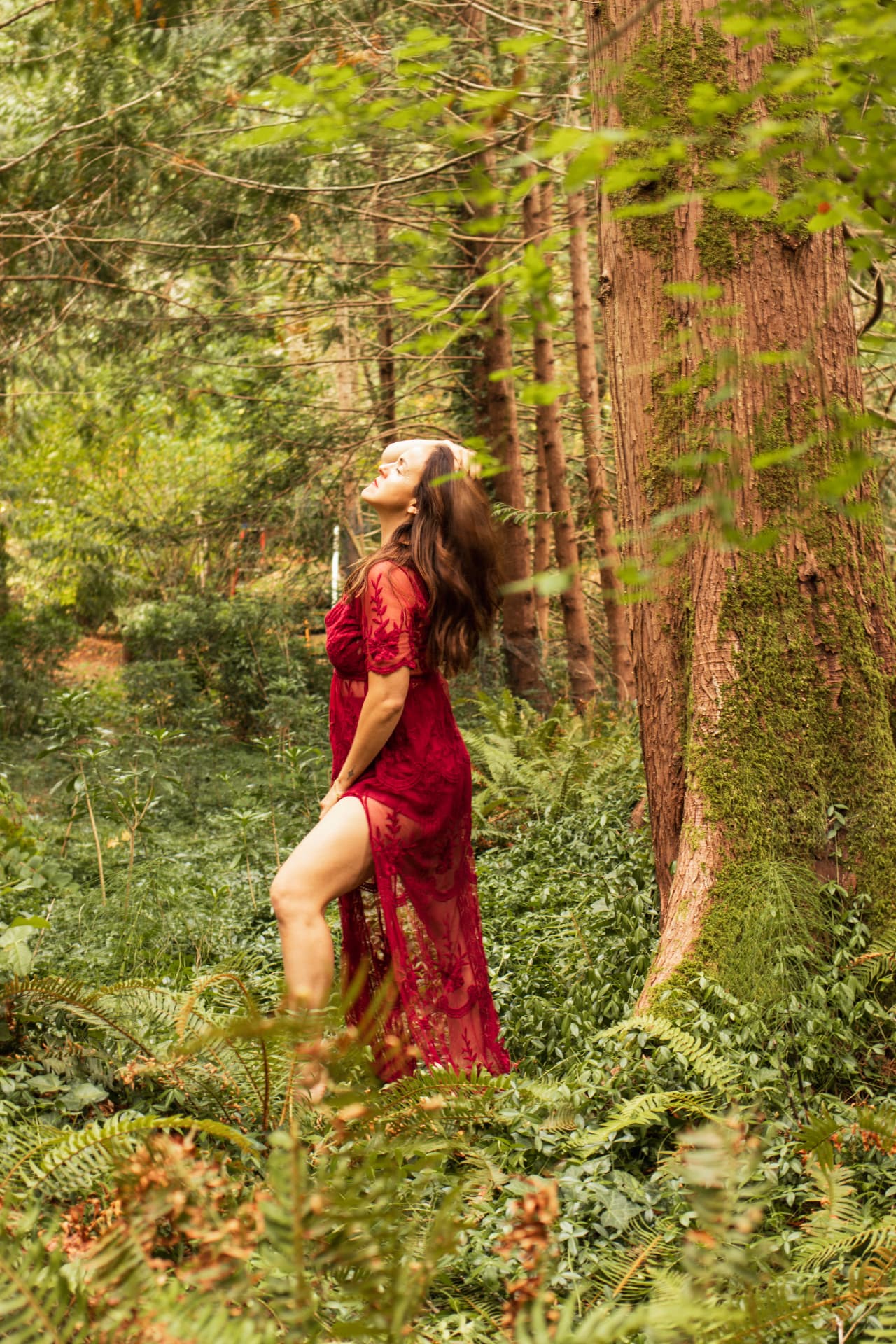 A woman in a red lace dress leaning back in the sunlight