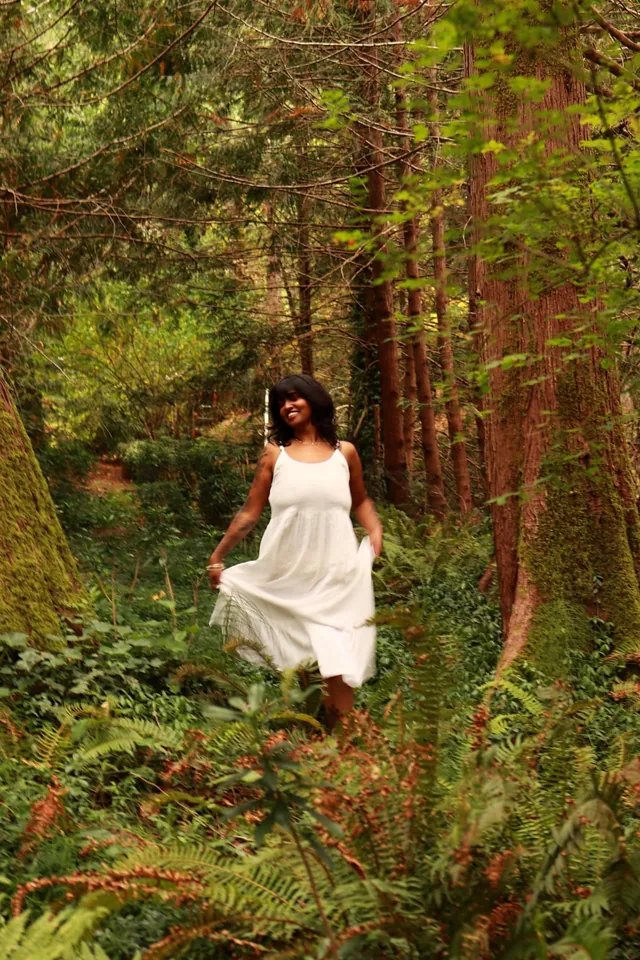 A woman in a white dress smiling among the ferns