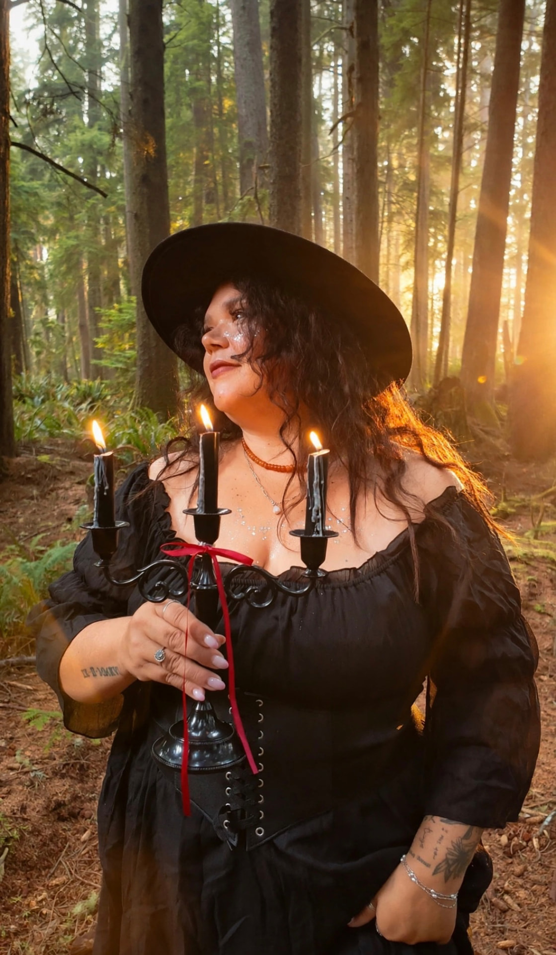 A woman holding a lit candelabra in the golden forest light